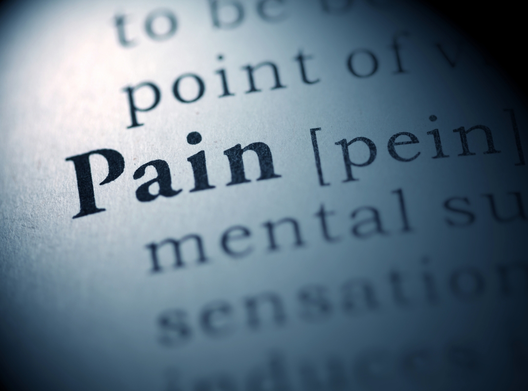 Close up of the definition for pain in a dictionary.