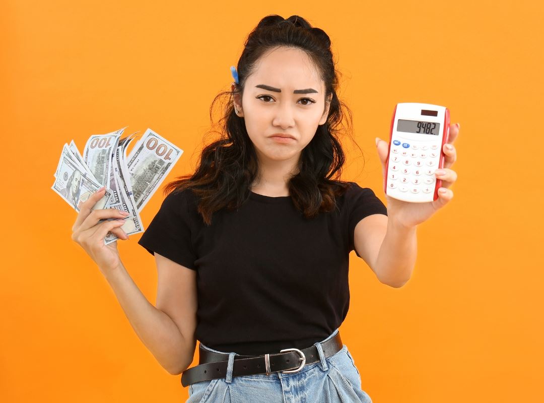 Woman holding calculator and money.